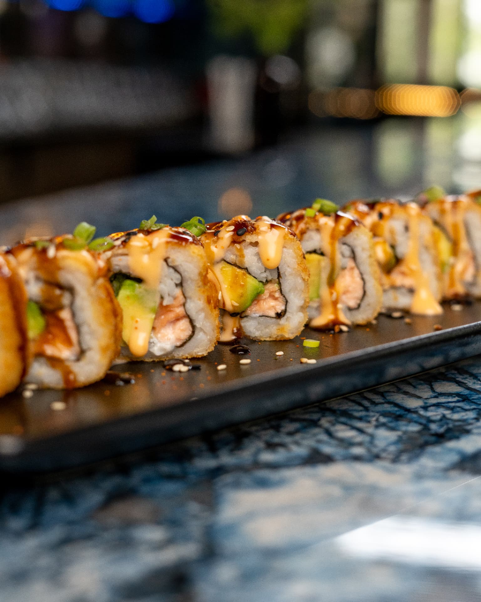 Sauced sushi rolls with warm bar lighting at Jozi Gin